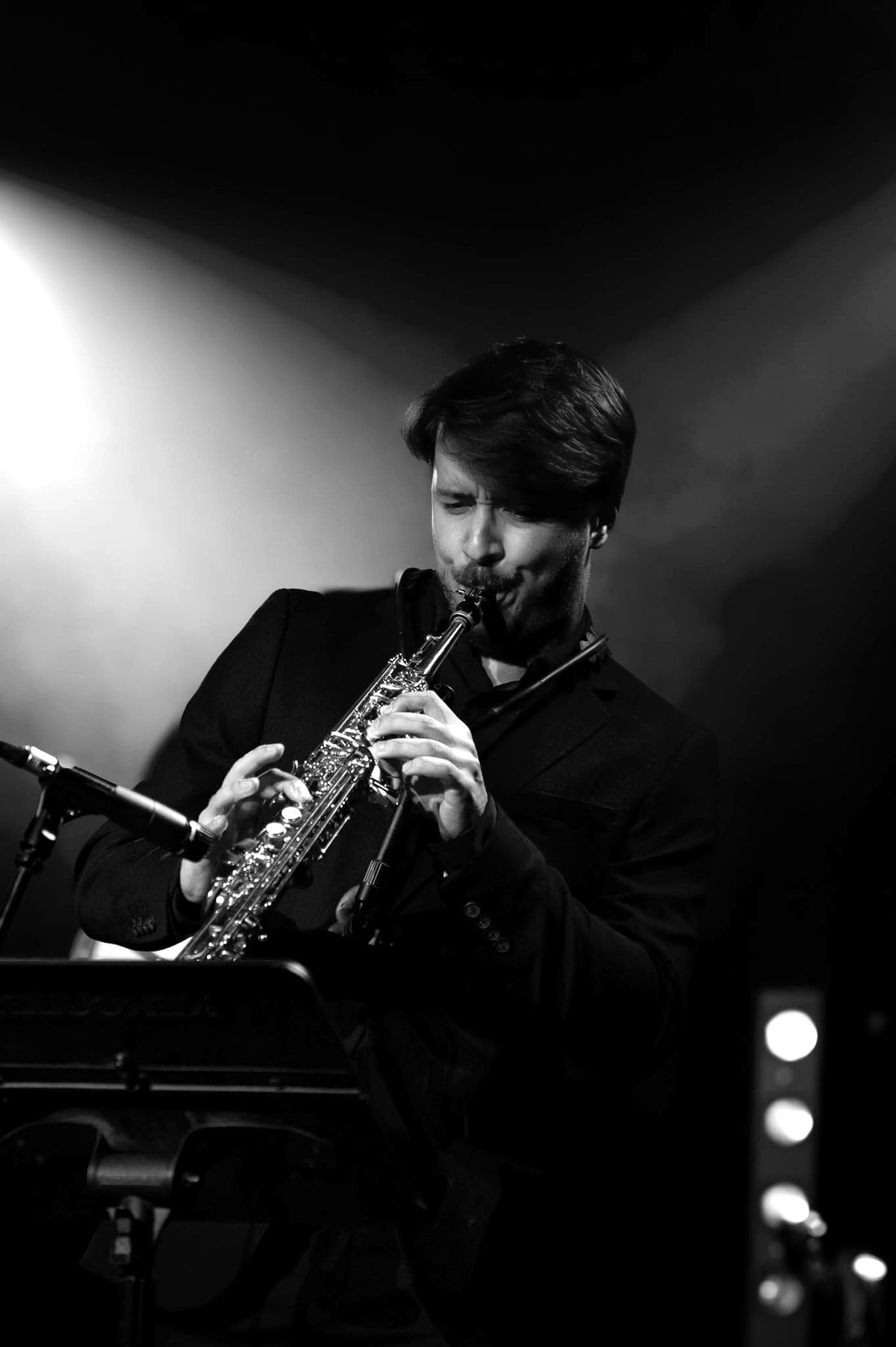 Filip Szostek grający na saksofonie sopranowym na scenie, w świetle reflektorów